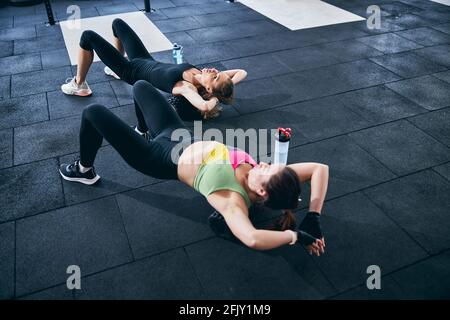 Curly-haired sportswoman performing an upper back exercise Stock