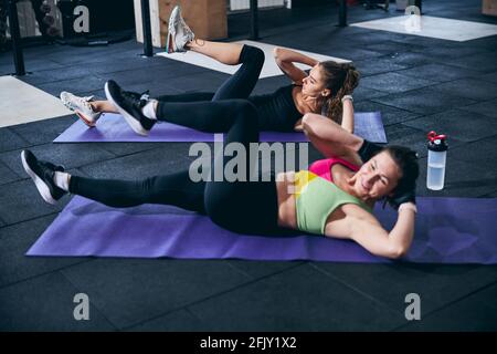 Serious lady and her personal trainer working their abdominal muscles Stock Photo