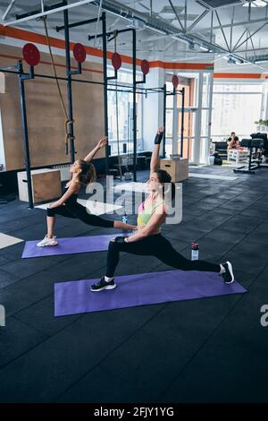 Woman and her personal trainer doing a stretching exercise Stock Photo