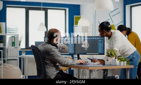 Professional heavy industry team of engineers working on computer with two monitors using CAD software with integrated development environment to design industrial machinery component. Stock Photo