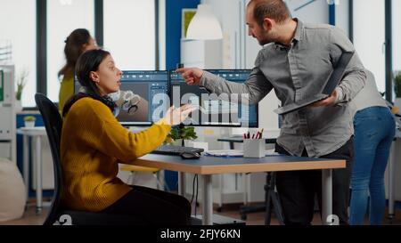 Professional workers using high-tech industrial program working on computer at mechanical piece design cad, sharing ideas about project using dual displays setup. Mnager analysing 3D gears shapes Stock Photo