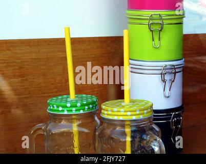 glass jars with colorful metal lid. ceramic air tight containers with rubber seal. plastic straw. kitchen accessories. display in store window. Stock Photo