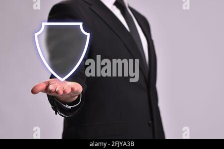 Man in a business suit shows a shield, the concept of protection and guarding Stock Photo