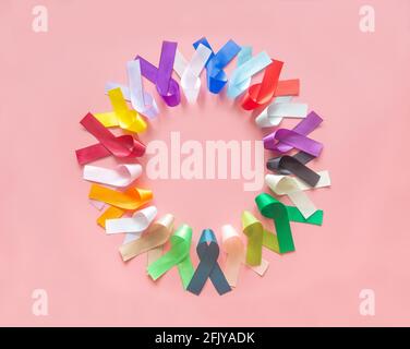 Colorful ribbons bow on pastel pink background in top view flat lay with copy space for text. World cancer day campaign concept on February 4, cancer Stock Photo