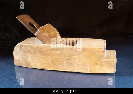 An old wooden plane on a table with a reflection. Carpenter's tool on a black background Stock Photo