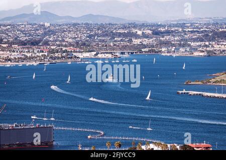 sailboats and harbor cruise ships leave their wakes on the west end of the San Diego Bay with the city and blurred mountains in the background Stock Photo