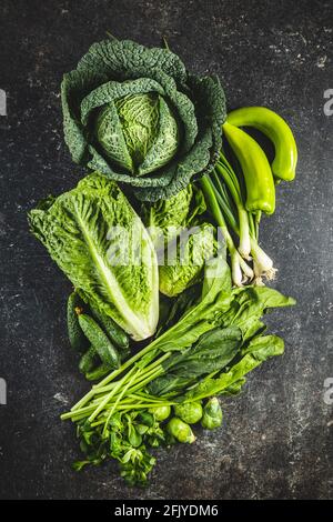 Different types of green vegetables on black table. Top view. Stock Photo