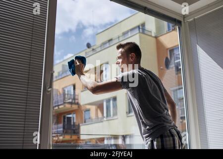 Man cleaning window with rag at home. Themes housework and housekeeping. Stock Photo