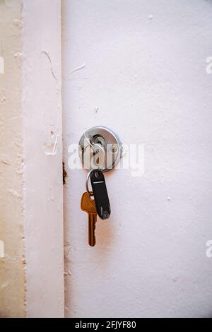 A key with a blank label in the keyhole of an old white door Stock Photo