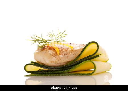 Grilled fish fillet on zucchini slices with dill and lemon isolated on white background. Stock Photo