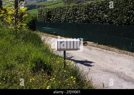 A white mailbox on the side of the road (Pesaro, Italy, Europe) Stock Photo