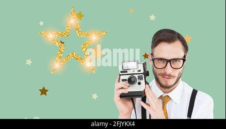 Composition of man holding retro camera and stars on green background Stock Photo