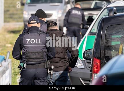 27 April 2021, Hessen, Frankfurt/Main: Customs officers lead a man for identity checks during a raid at a cleaning company. After months of preliminary investigations, customs, with the support of special units and federal police, had searched several residential and commercial buildings in the Rhine-Main area, in Cologne and near Passau. The main focus of the operation was in the Frankfurt city area. Photo: Boris Roessler/dpa Stock Photo