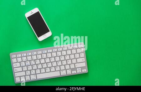small wireless keyboard and mobile phone, on green background Stock Photo