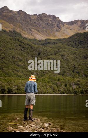 Rear View of a Tramper Fishing in the Mavora Lakes, near Mossburn, South Island, New Zealand Stock Photo