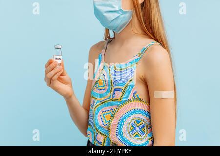 Vaccination of a little girl, a small child with an adhesive plaster on his hand and holding a bottle with a vaccine against coronavirus covid-19, flu Stock Photo