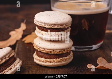 Cup of coffee and chocolate macarons on wooden background. Cozy autumn composition - Image Stock Photo