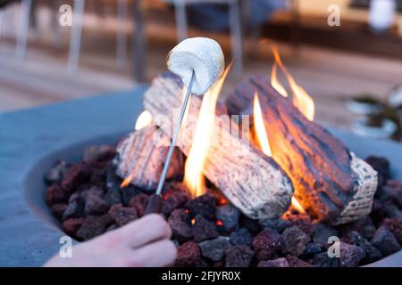 Roasting marshmallow over a gas fire while glamping Stock Photo