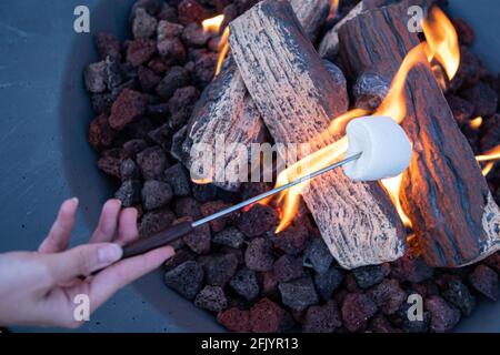 Roasting marshmallow over a gas fire while glamping Stock Photo