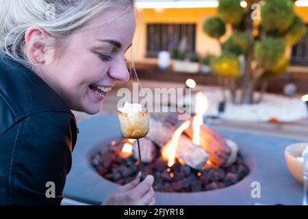 Roasting marshmallow over a gas fire while glamping Stock Photo