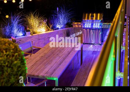 Gas barbecue on a stylish illuminated wooden terrace Stock Photo