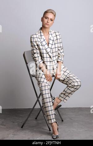Elegant ant charismatic short blond haired and natural makeup businesswomen wearing oversized linen suit with blue stripes posing isolated in studio Stock Photo