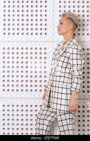 Elegant ant charismatic short blond haired and natural makeup businesswomen wearing oversized linen suit with blue stripes posing isolated in studio Stock Photo