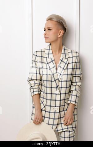 Elegant ant charismatic short blond haired and natural makeup businesswomen wearing oversized linen suit with blue stripes posing isolated in studio Stock Photo
