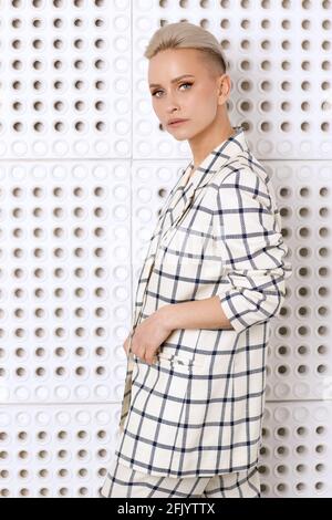 Elegant ant charismatic short blond haired and natural makeup businesswomen wearing oversized linen suit with blue stripes posing isolated in studio Stock Photo