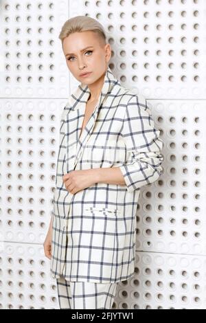Elegant ant charismatic short blond haired and natural makeup businesswomen wearing oversized linen suit with blue stripes posing isolated in studio Stock Photo