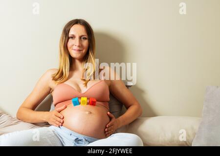 Boy word made of toy blocks on big pregnant belly Stock Photo