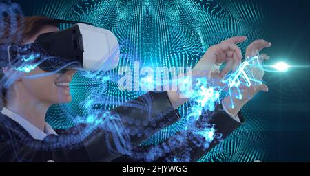 Composition of green light trails over woman wearing vr headset and touching virtual screen Stock Photo