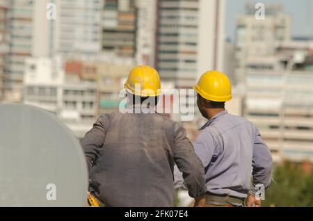 construction workers resting on working hours. with work clothes and tools on the terrace of the building overlooking the city Stock Photo