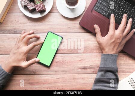 top view of man hand using smart phone and typing on laptop  Stock Photo
