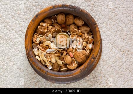 Walnut on brass in vintage wooden nut bowl with cracked walnut and peanut shells Stock Photo