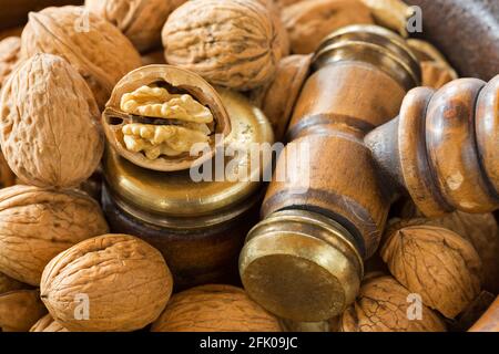 Opened Walnuts in vintage wooden nut bowl with brass Nutcracker gavel hammer Stock Photo