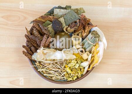 Bowl full of dried Chinese mixed herbs to make cooling drinks in traditional Chinese medicine on wooden background Stock Photo