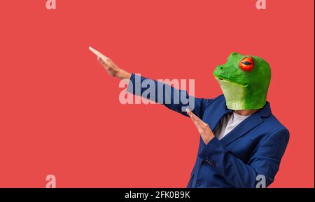 man with googly-eyed frog mask euphoric and celebrating with arms on red background with copy space Stock Photo