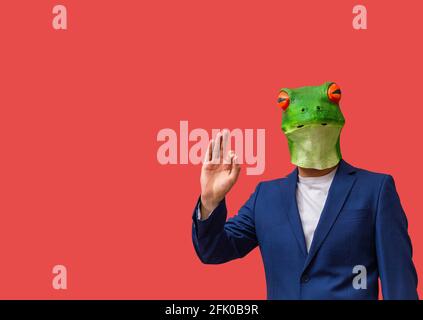 man with googly-eyed frog mask marking approval with his hands 'Ok' on red background with copy space Stock Photo