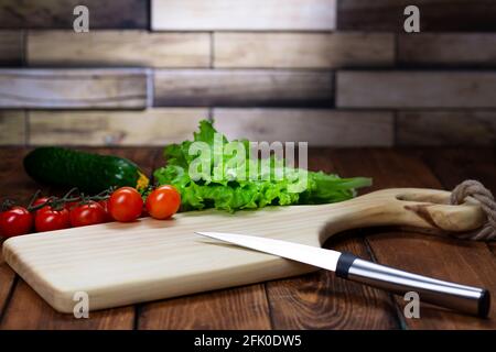 Cutting board on a wooden table. Handmade chopping board. Fresh vegetables and cutting board Stock Photo