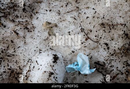 Photo of throwed used medical mask on the dirt snow Stock Photo