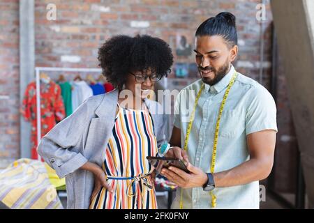 Smiling diverse male and female designers using tablet and talking Stock Photo