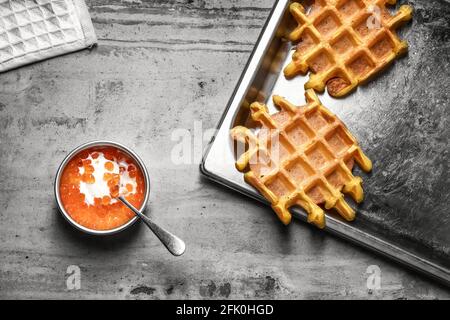 Traditional Belgian waffles on a baking silver tray with red caviar on grey clay background. Top view, copy space. Stock Photo