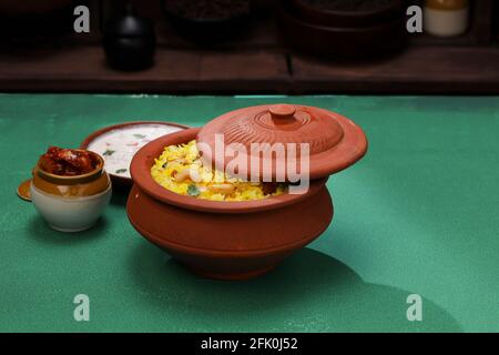 Indian  Biryani , kerala style  biriyani made using jeera rice and spices arranged in an earthenware with raitha and lemon pickle as side dish placed Stock Photo