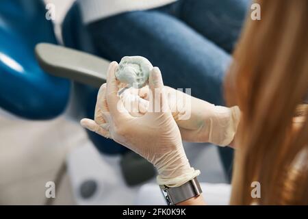 Orthodontist using dental putty to make teeth impressions of a