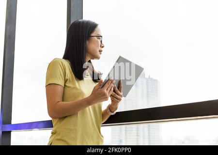 Bussines woman holding tablet standing next to office window. Stock Photo