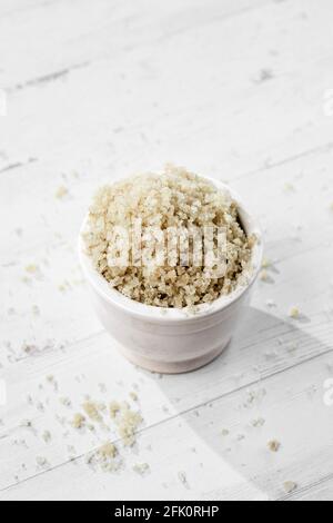 closeup of some gray celtic sea salt in a white ceramic bowl, on a white wooden table Stock Photo