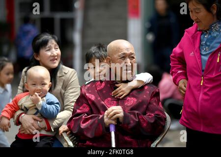 (210427) -- TAIYUAN, April 27, 2021 (Xinhua) -- Hu Zaizhong takes a rest with family members at Xuejiawan Village, Liulin County, Lyuliang City of north China's Shanxi Province, on April 24, 2021. Hu Zaizhong, who has just turned 100, vividly remembers his wishes at different stages of his life: having decent food and clothing in his early days, teaching as many pupils as he could in his prime age, and enjoying quality time with his family for late years. Nonetheless, Hu made a new wish before blowing the candles on his birthday cake. All members of Hu's extended family flocked home on April 2 Stock Photo