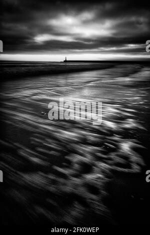 A black and white portrait photo of Roker Lighthouse at the mouth of the River Wear in Sunderland, a city in the north east of England. Stock Photo
