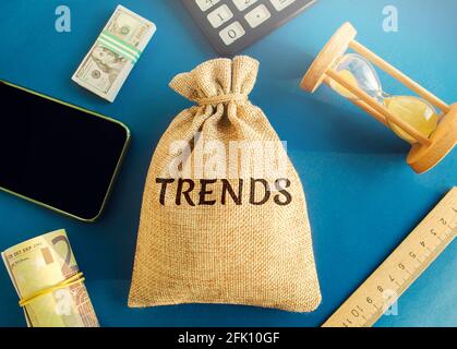 Money bag with the word Trends. Popular and relevant topics. New ideological trends. Recent and latest trend. Evaluation methods. Phone, hourglass, mo Stock Photo